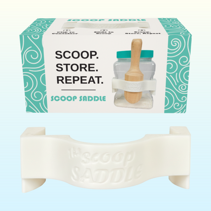 The Scoop Saddle retail packaging and white clip, designed to hold wooden scoops securely on Buff City Soap laundry detergent jars.